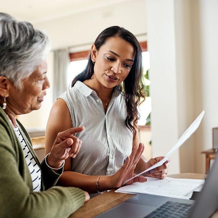 Mother and daughter at the dining table talking to each other about fraud prevention.